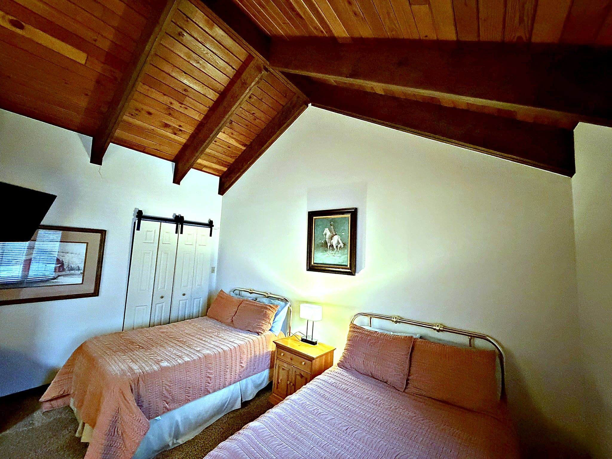 Third bedroom with two double beds under vaulted wood-beam ceiling