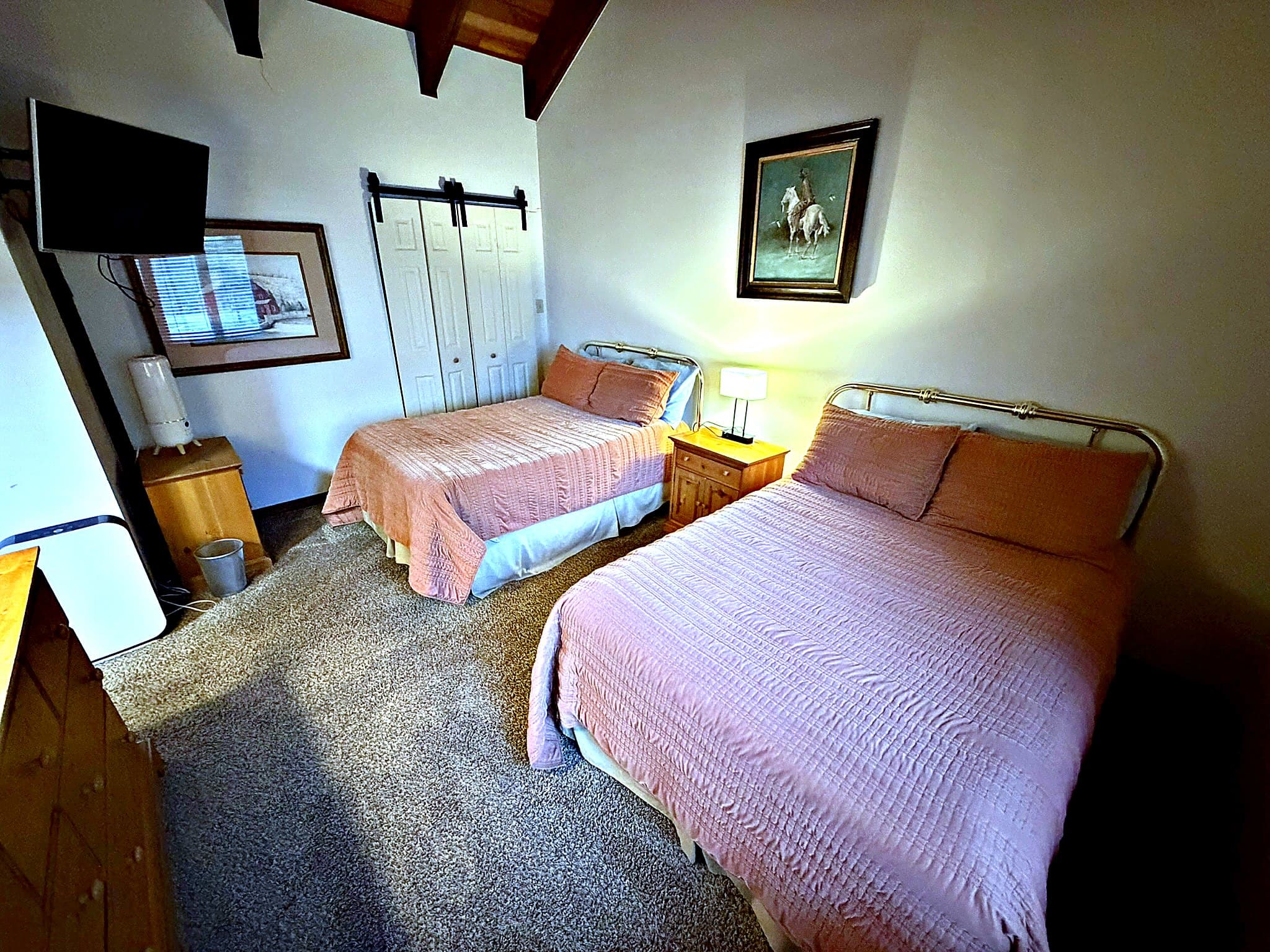 Upper-level bedroom with two beds and beam ceiling