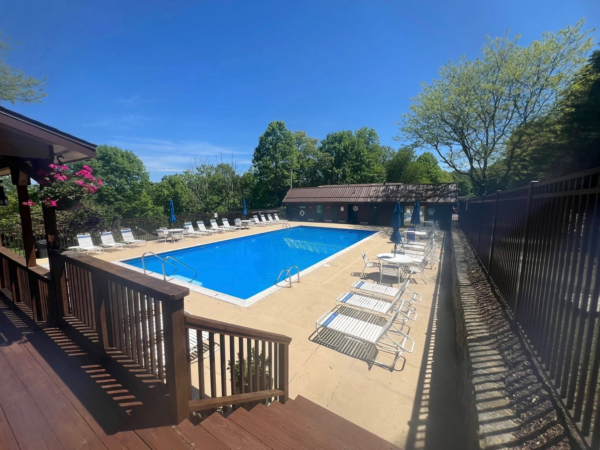 Community outdoor pool and sun deck framed by Laurel Highlands woods